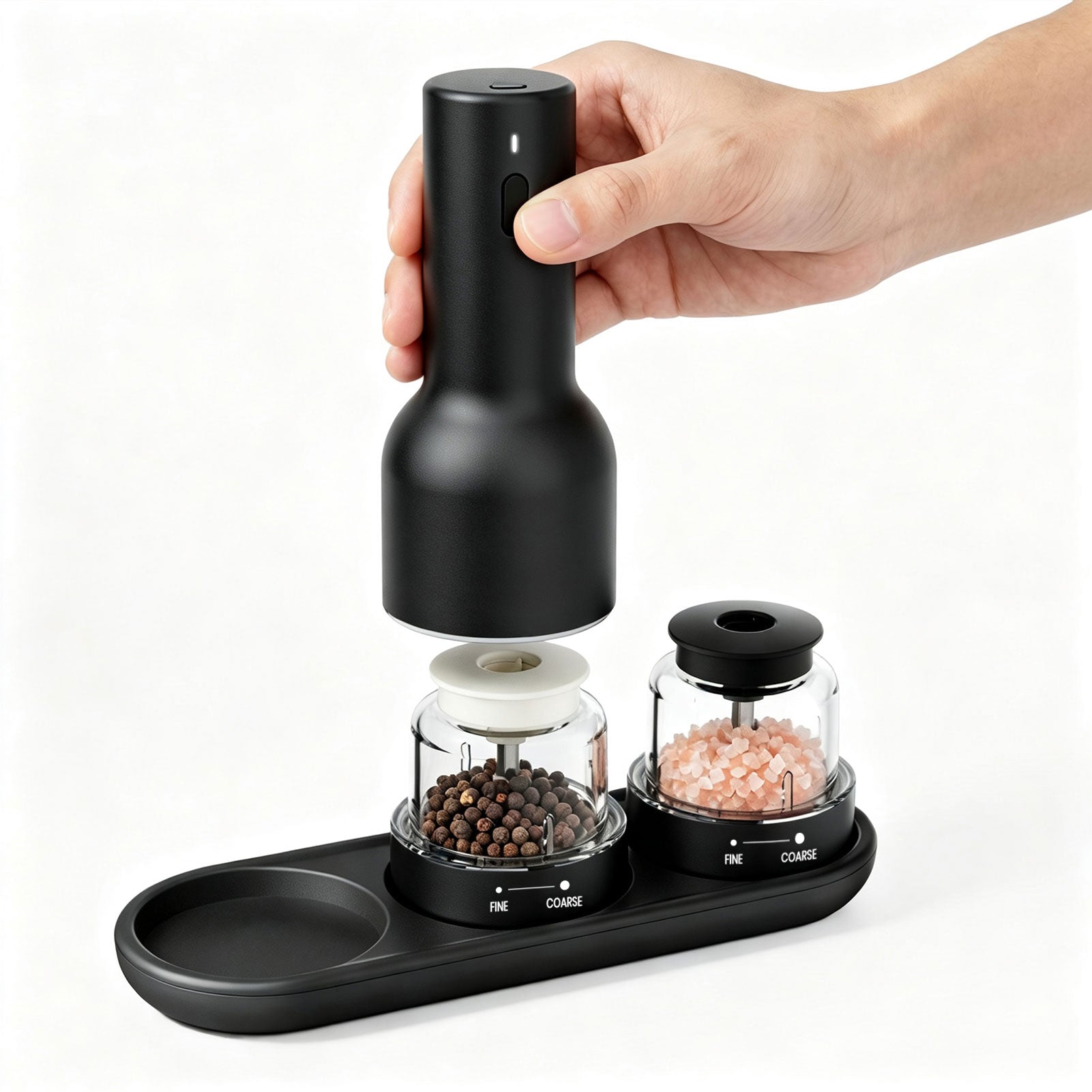 Black electric pepper grinder with a hand holding it above a white background